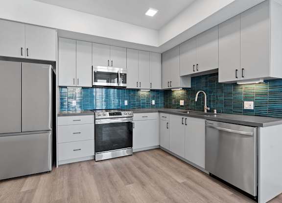 Modern kitchen with blue glass tile backsplash at AMP 30 Apartments, San Diego, 92116