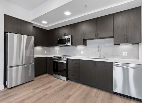 L shaped kitchen with dark wood cabinets at AMP 30 Apartments, San Diego, California