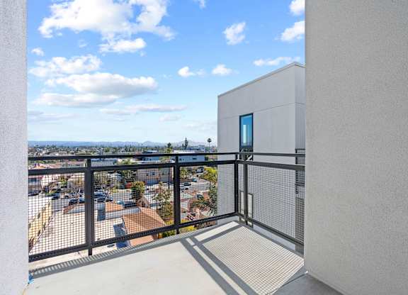 Private balcony with mesh railing overlooking cityscape at AMP 30 Apartments, San Diego, CA 92116