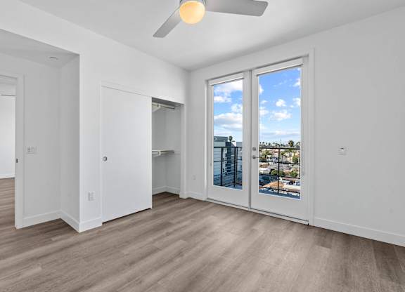 Empty bedroom with closet and balcony doors at AMP 30 Apartments, San Diego, California