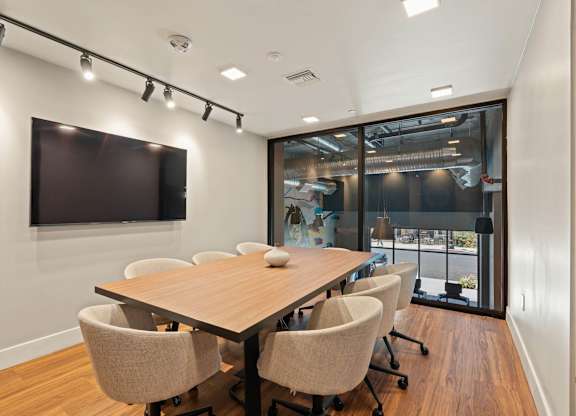 Conference room with large screen and wood table at AMP 30 Apartments, San Diego