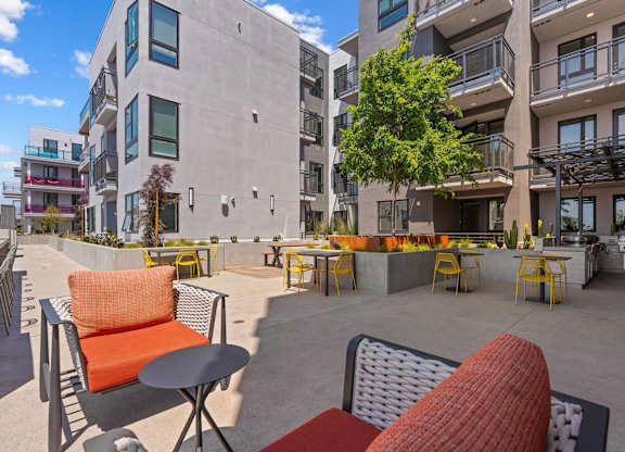 Outdoor courtyard with dining tables and grilling station at AMP 30 Apartments, San Diego, CA
