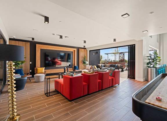 Resident lounge with red seating and outdoor patio access at AMP 30 Apartments, California