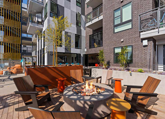 Outdoor fire pit seating area with wooden deck at AMP 30 Apartments, San Diego, CA