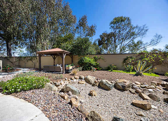 A house with a patio and a rock garden in front.