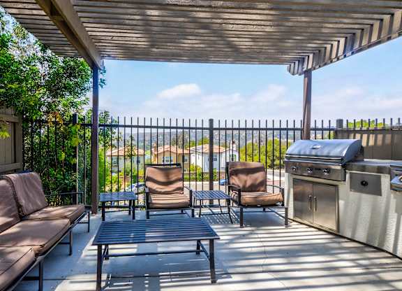 A patio with a table, chairs and a grill.