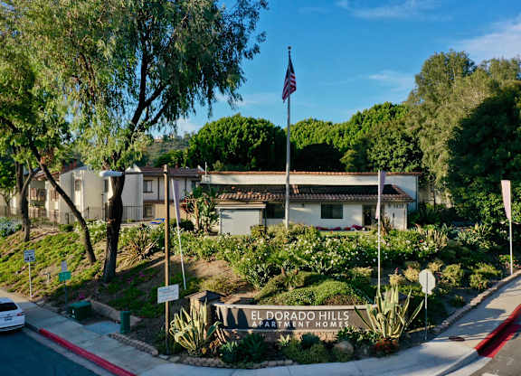 The image shows a sign for El Dorado Hills Community Homes with a flag flying in the background.