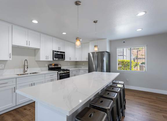 A kitchen with white cabinets and a marble countertop.