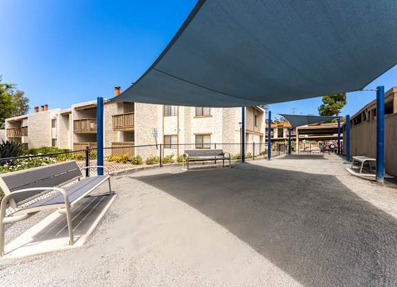 A playground with a blue canopy and a bench is in the foreground.