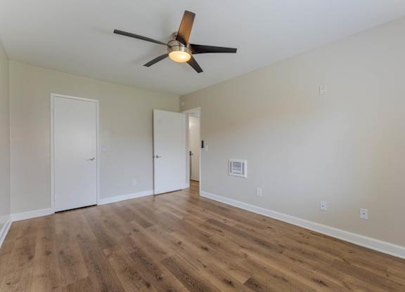 A room with a ceiling fan and wood flooring.