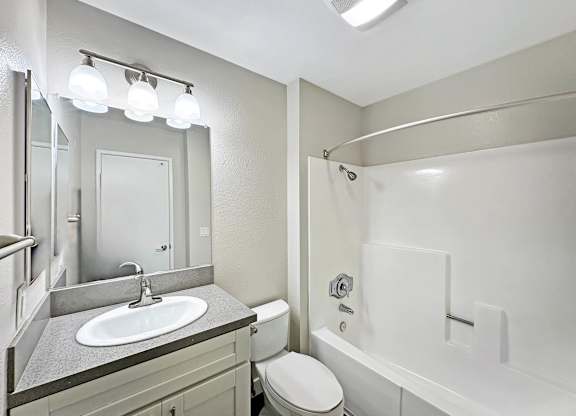 A bathroom with a white toilet, sink, and bathtub.