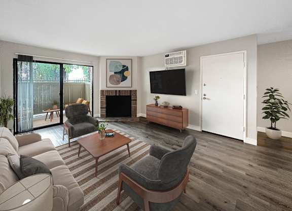 A living room with a grey sofa, a grey armchair, a wooden coffee table, a fireplace, and a television on the wall.