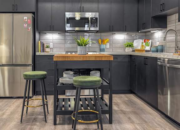 Modern kitchen with island seating and wood countertop at AMP 30 Apartments, San Diego, CA