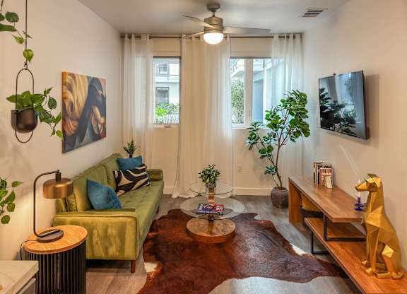 Living room with green sofa and natural light at AMP 30 Apartments, San Diego, 92116