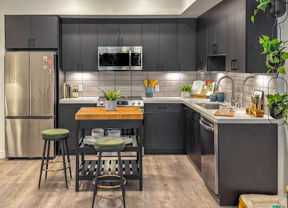 Modern kitchen with dark cabinets and island workspace at AMP 30 Apartments, California