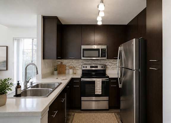A modern kitchen with dark brown cabinets and stainless steel appliances.