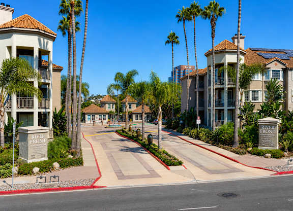 A street view of a residential area with palm trees and apartment buildings.
