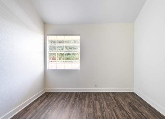 A room with a window and wooden flooring.
