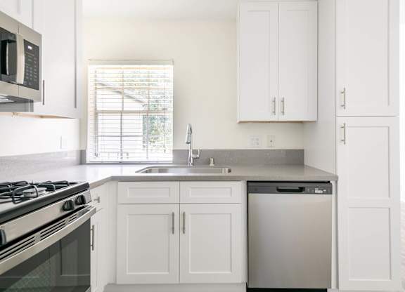 A kitchen with white cabinets and a black stove top.
