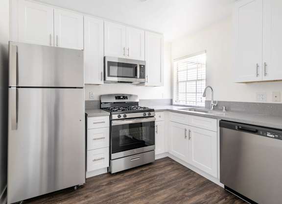 A modern kitchen with white cabinets and stainless steel appliances.