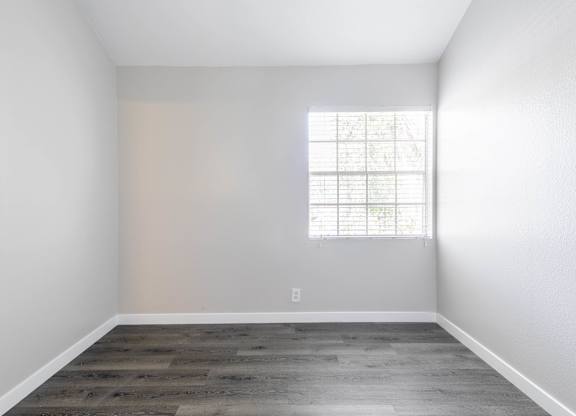 A room with a window and wooden flooring.