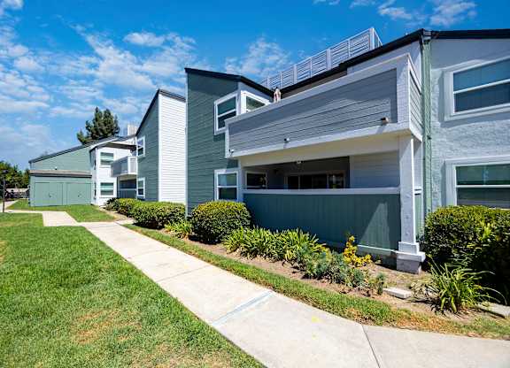 A modern two-story house with a grey and white exterior and a green lawn in front.