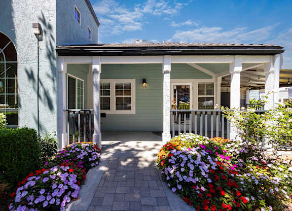 A house with a white porch and a flower bed in front.