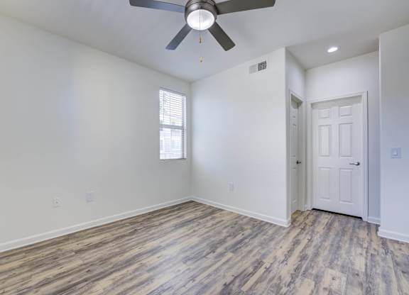 A room with a ceiling fan and a door.