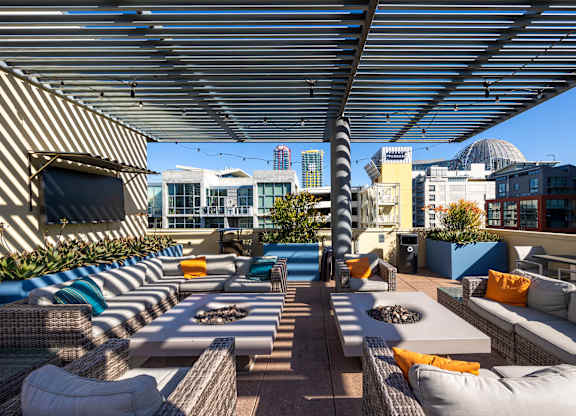 A rooftop patio with a striped awning and a fire pit.
