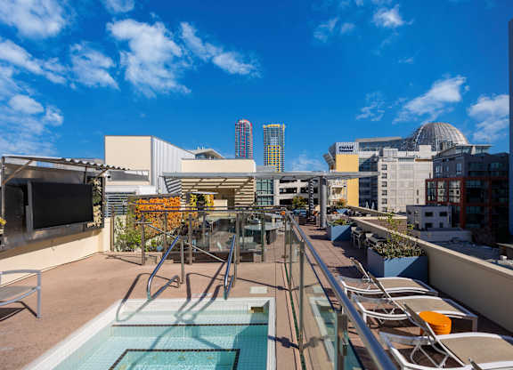 A rooftop pool with lounge chairs and a city skyline in the background.