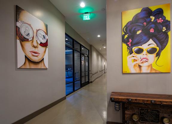 A hallway with two paintings on the wall and a wooden bench.