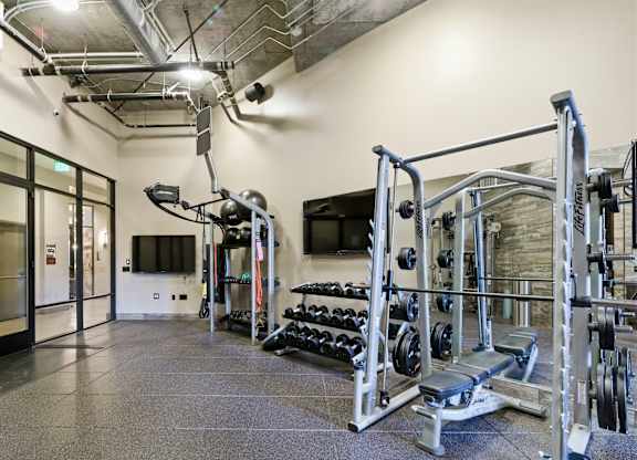 A gym with a variety of equipment including a squat rack, bench press, and a barbell.