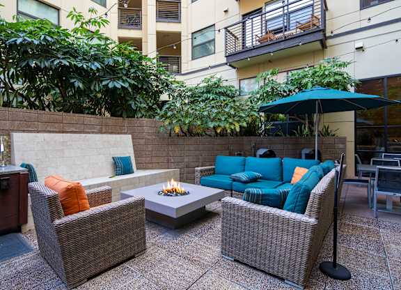 A patio with a fire pit and wicker furniture.