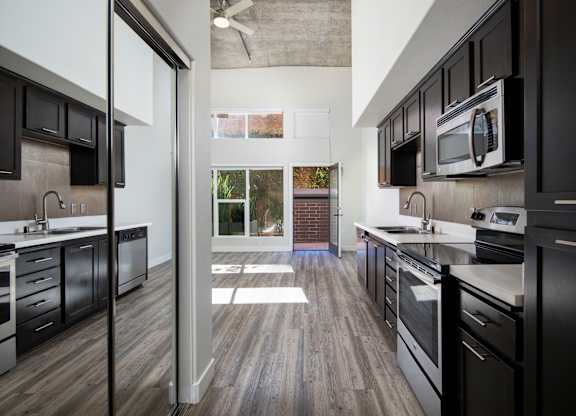 A modern kitchen with black cabinets and stainless steel appliances.