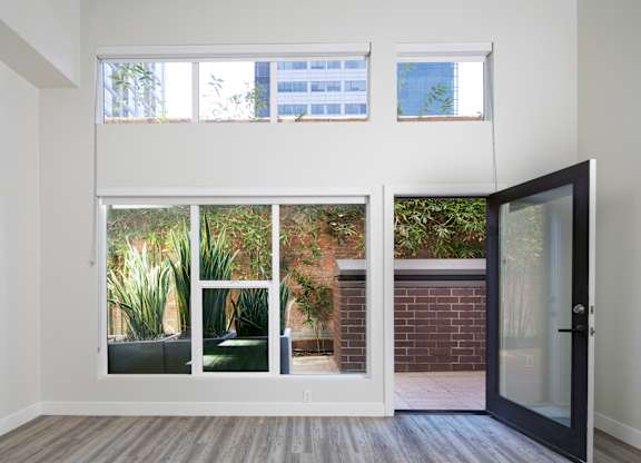 A room with a view of a garden through the windows.