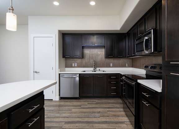 A modern kitchen with dark wood cabinets and white countertops.