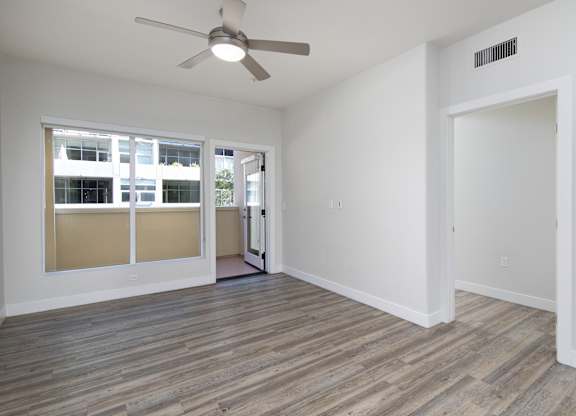 A room with a ceiling fan and a door leading to another room.