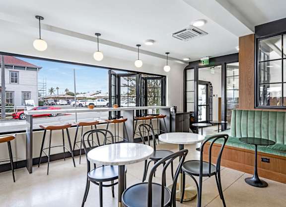 A restaurant with tables and chairs and a view of the outside.