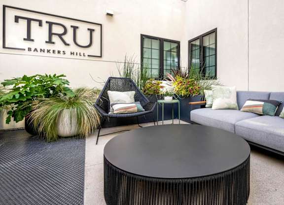 A black round table is in the middle of a patio with a couch and chairs.