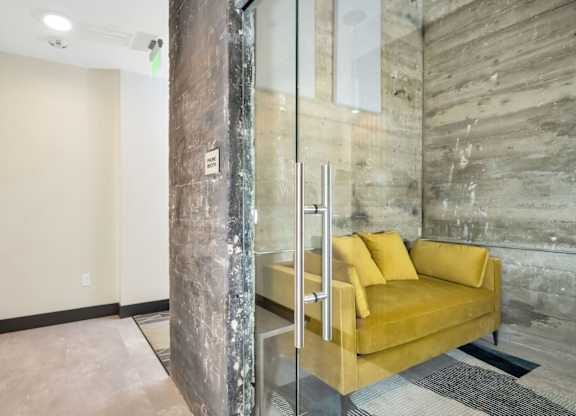 A room with a yellow couch and a wooden pillar.