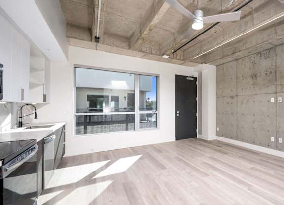 A spacious room with a kitchen area and a ceiling fan.