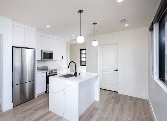 A modern kitchen with a white island and stainless steel appliances.