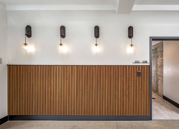 A hallway with a wooden wall and three wall lights.