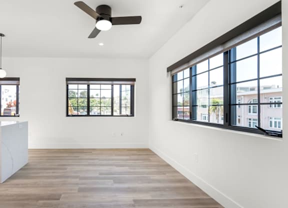 A kitchen with a stainless steel trash can and wooden flooring.