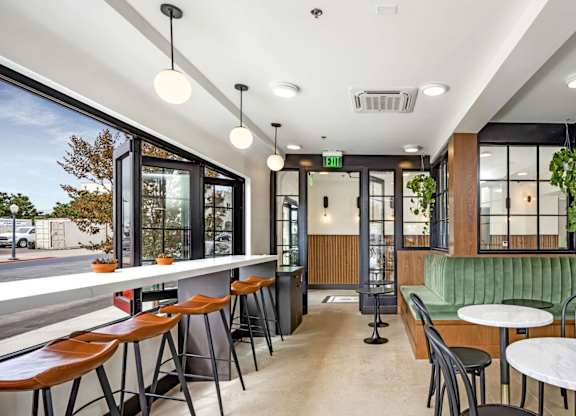 A modern restaurant with a green booth and wooden tables.