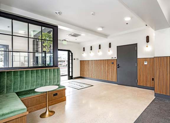 A modern waiting room with green couches and a wooden bench.
