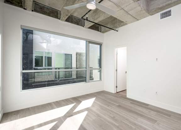 A room with a large window and a wooden floor.