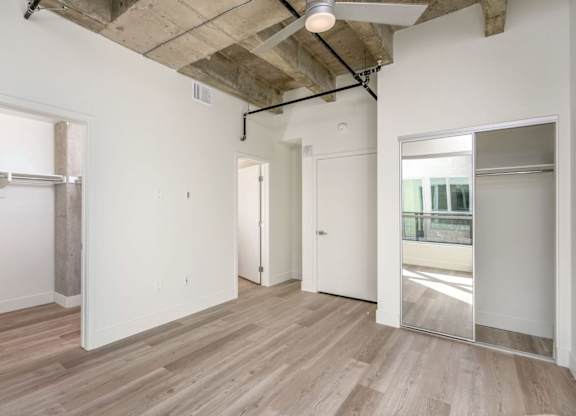 A room with wooden floors and white walls, with a doorway leading to another room.
