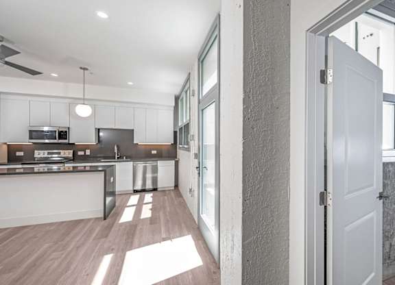 A modern kitchen with a white door and a wall with pipes.