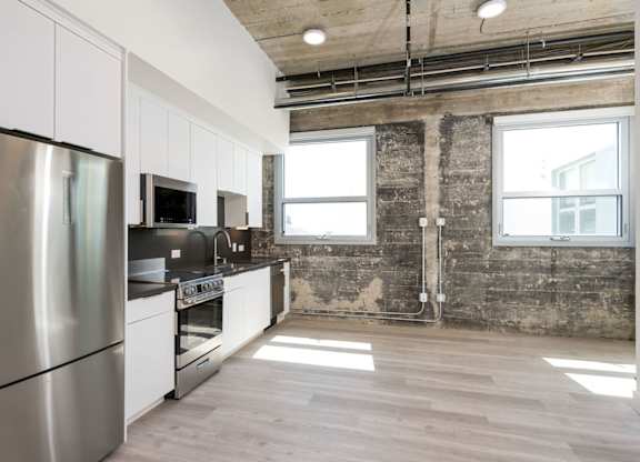 A kitchen with stainless steel appliances and wooden floors.